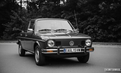 Vintage Eagle VW dealership sign displayed outside a classic Volkswagen showroom with Beetle and Golf models parked nearby.